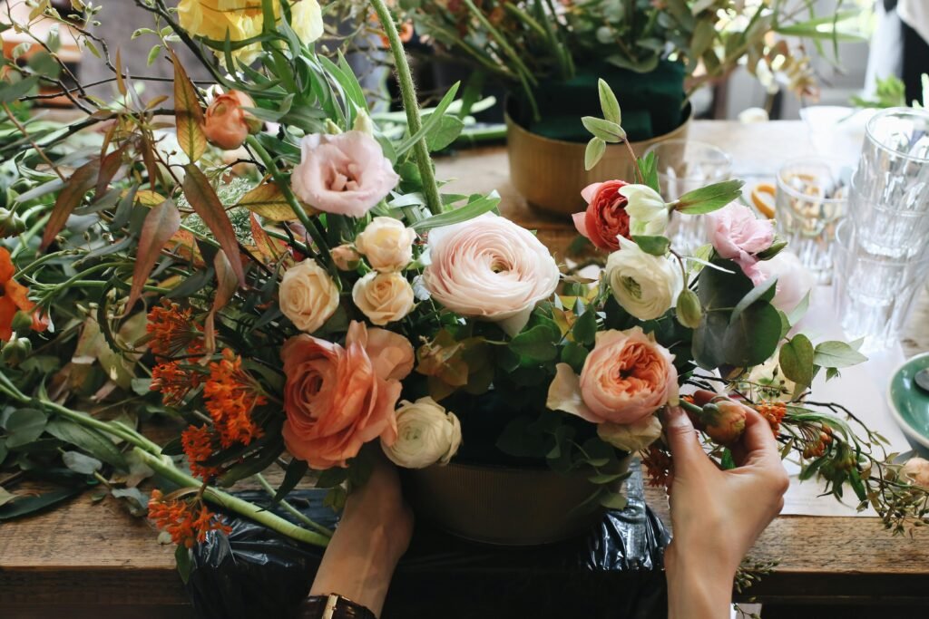 Colorful bouquet of roses and wildflowers being arranged in a bright workshop setting.